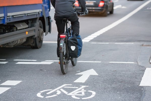 Ein Radfahrer fährt neben einem Lkw auf der Straße.